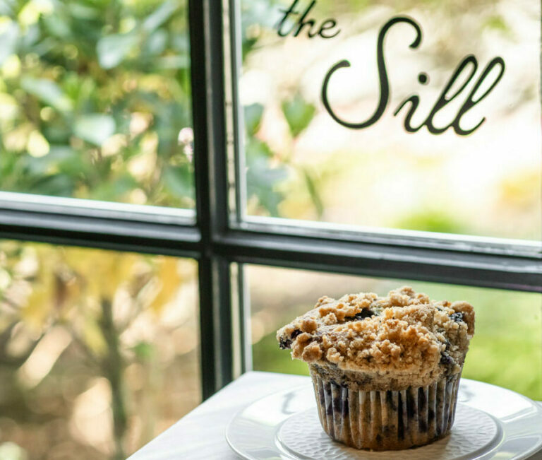 Three pastries sit on plates atop a table by a window with greenery and flowers outside; "the Sill" appears on the glass, evoking the relaxed atmosphere of a resort like Wequassett Resort & Golf Club.