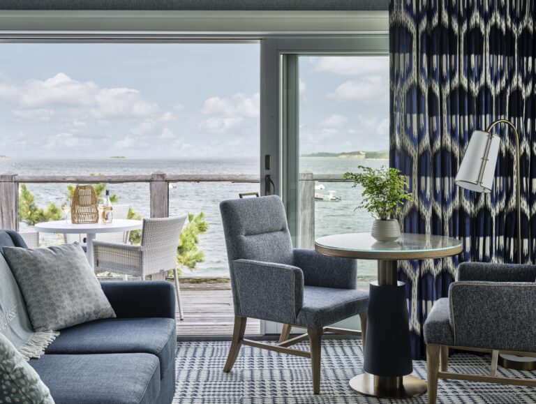 Scenic water view from a private balcony at Wequassett Resort, featuring outdoor dining furniture and a comfortable sitting area with patterned throw pillows.