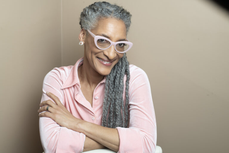 Woman smiling wearing pink shirt and glasses.