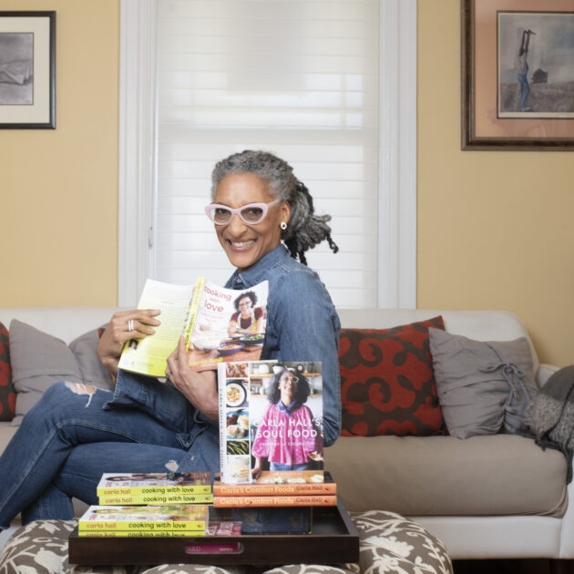 Woman smiling and siting on couch holding a magazine.