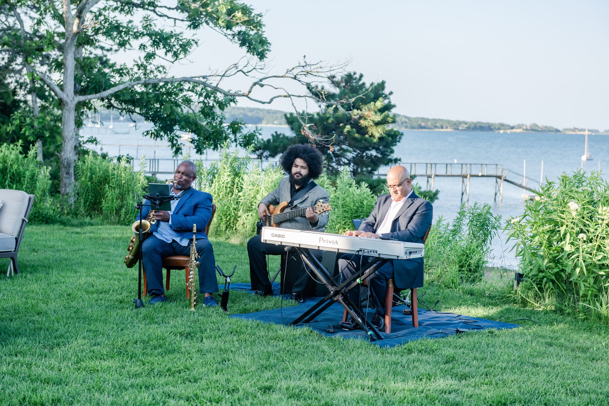 Band trio playing instruments on the lawn.