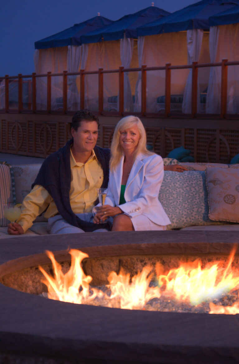 Couple smiling by fire.