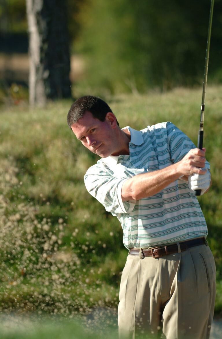Man swinging his golf club on a Cape Cod golf course.