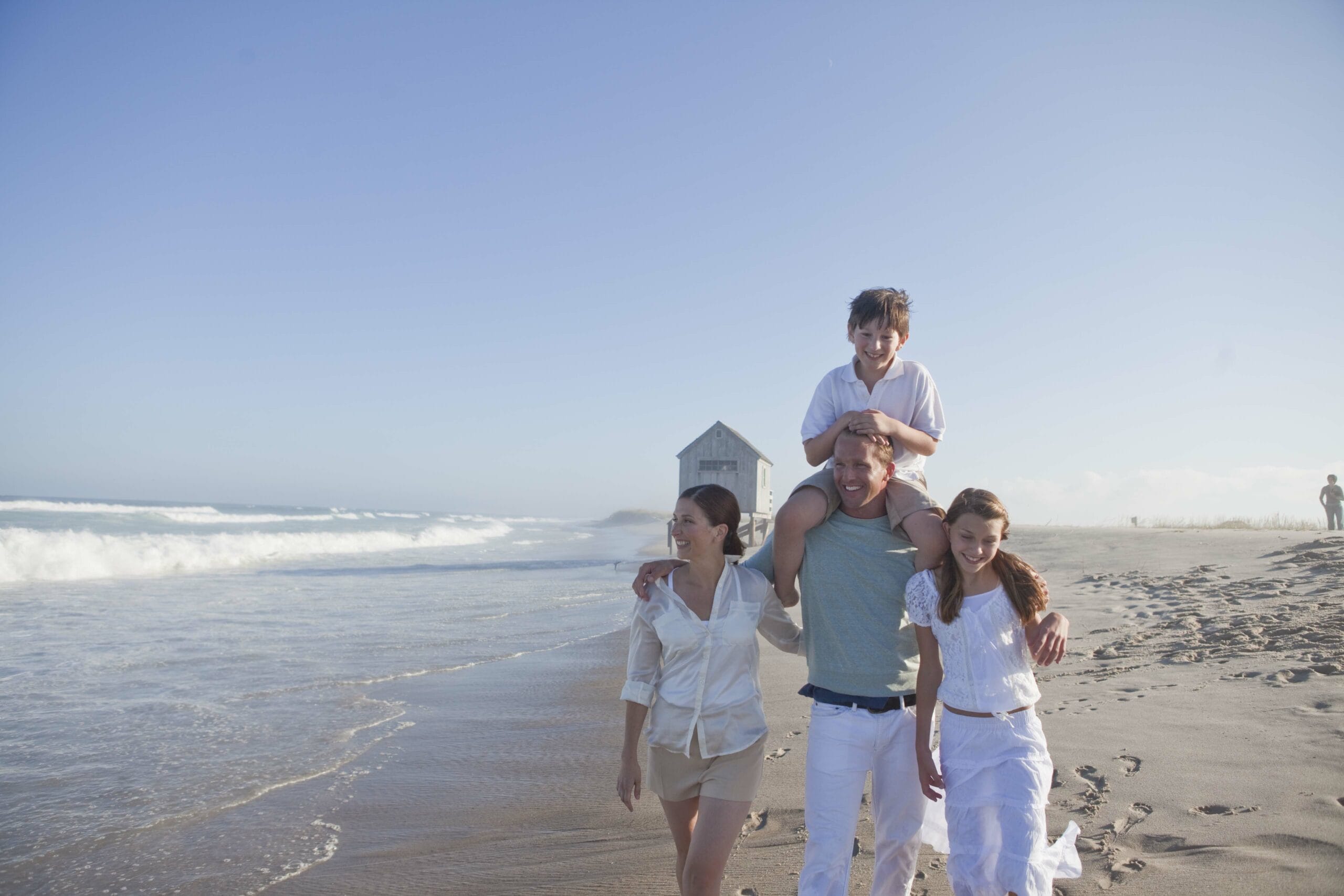 Family of four walking on the beach.