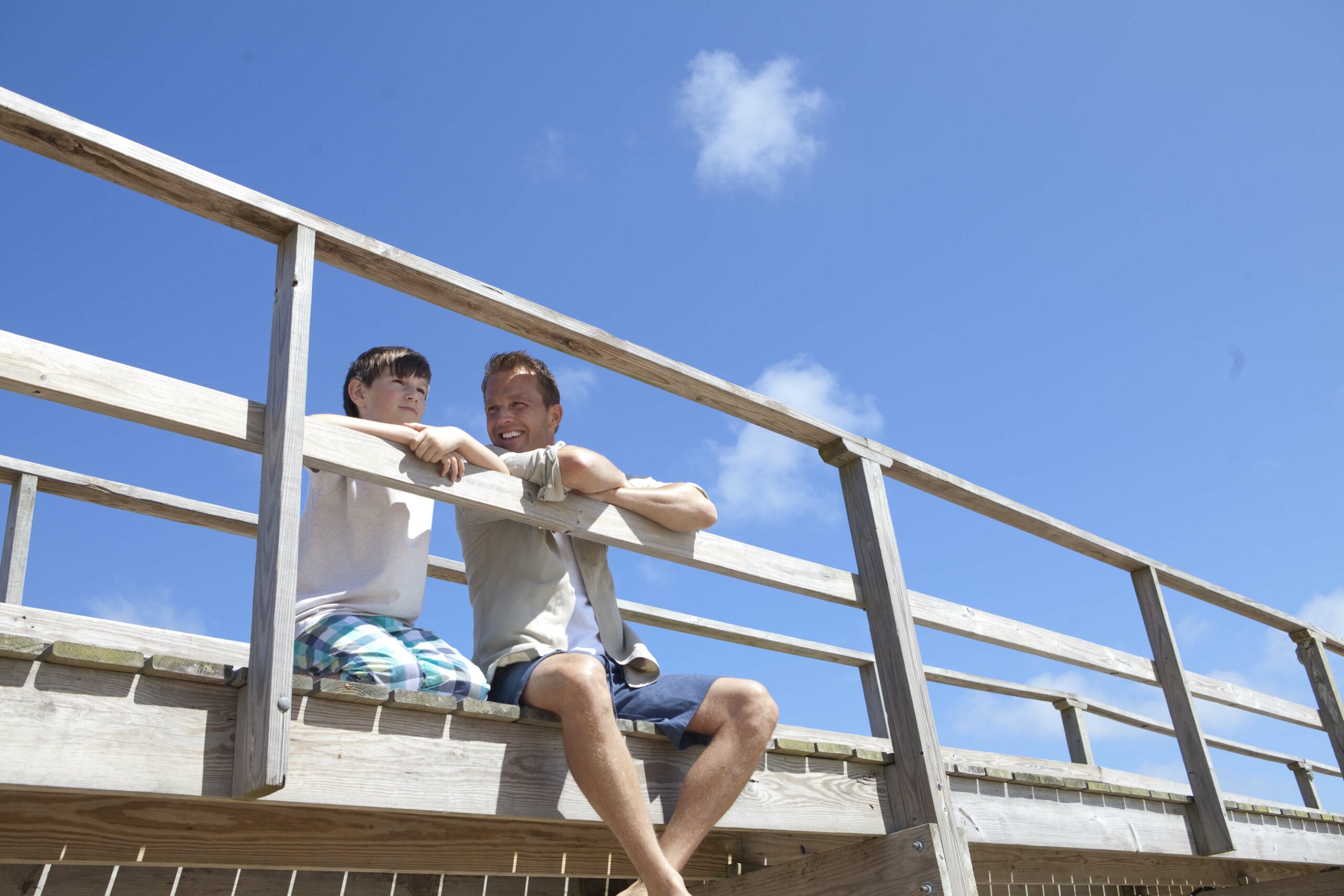 Father and son sitting on a dock.