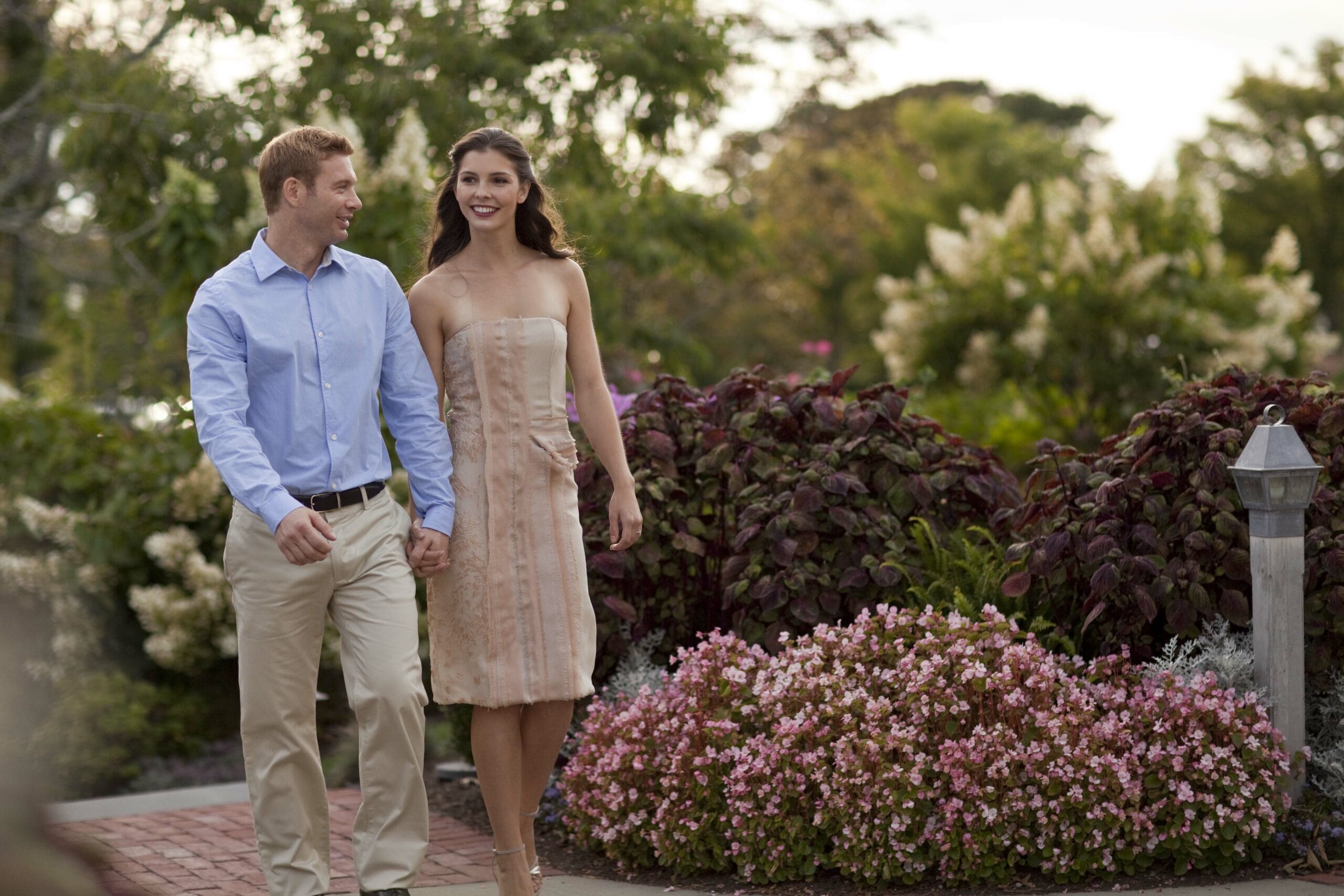 Man and woman holding hands and walking outside.