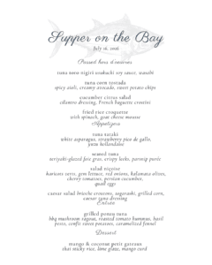 A beautifully printed menu titled "Supper on the Bay" invites guests to indulge in a selection of seafood-inspired hors d’oeuvres, enticing entrees, fresh salads, and decadent desserts, each course detailed with vivid descriptions that capture the essence of coastal dining.