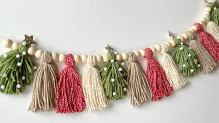 A decorative garland from our Garland Workshop, featuring wooden beads, yarn tassels in red, cream, and green, plus green yarn Christmas trees adorned with white pom-poms and gold star toppers—perfect for adding Nature’s Elegance to your holiday décor.