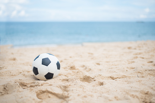 A black and white soccer ball sits on the sandy beach at Wequassett, framed by the ocean and sky—the perfect scene for a Summer of Soccer.