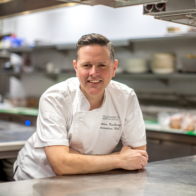 Man smiling wearing a chef's coat.
