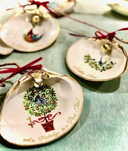 Three decorative seashell ornaments with illustrations and text referencing "The Twelve Days of Christmas," each tied with a red ribbon and gold trim—perfect for commemorating your Annual Baking Classic or festive Holiday Baking traditions.