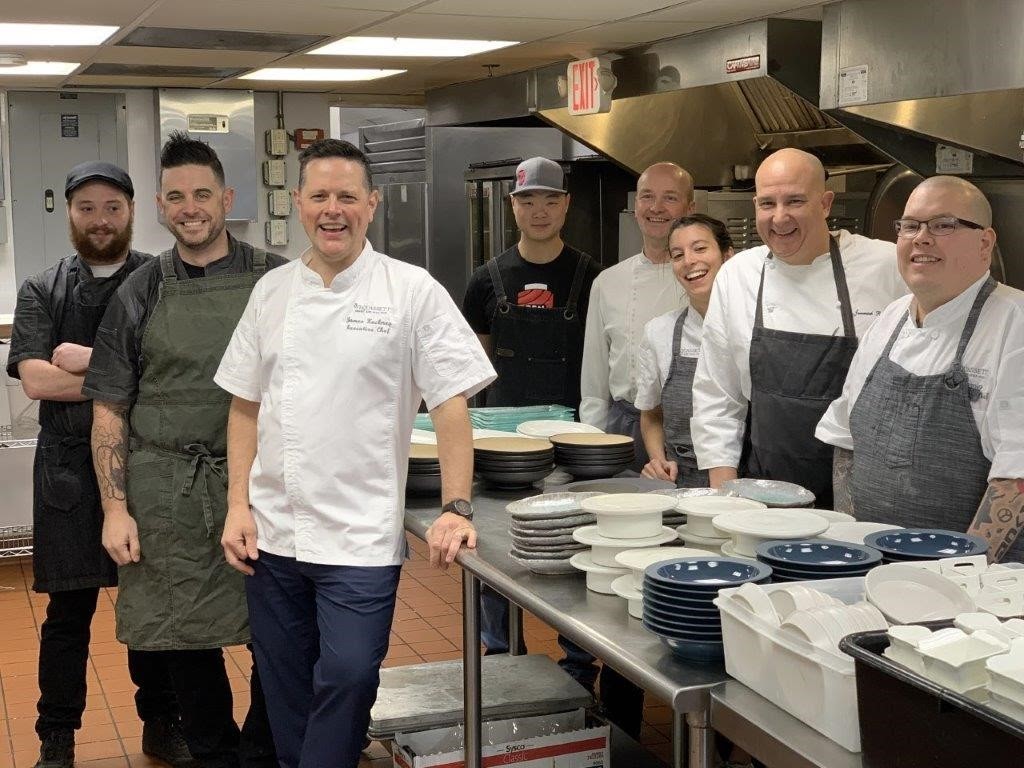 Group of chefs smiling in a kitchen.