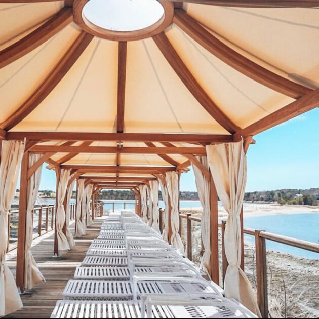 Lounge chairs under canopy on ocean.